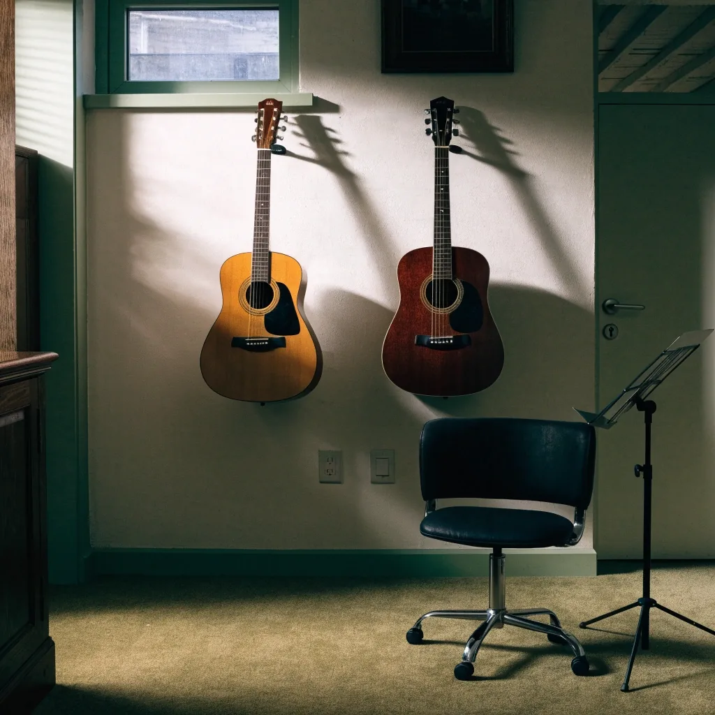 Two acoustic guitars hanging in a Brighton teaching room beside a stool and music stand