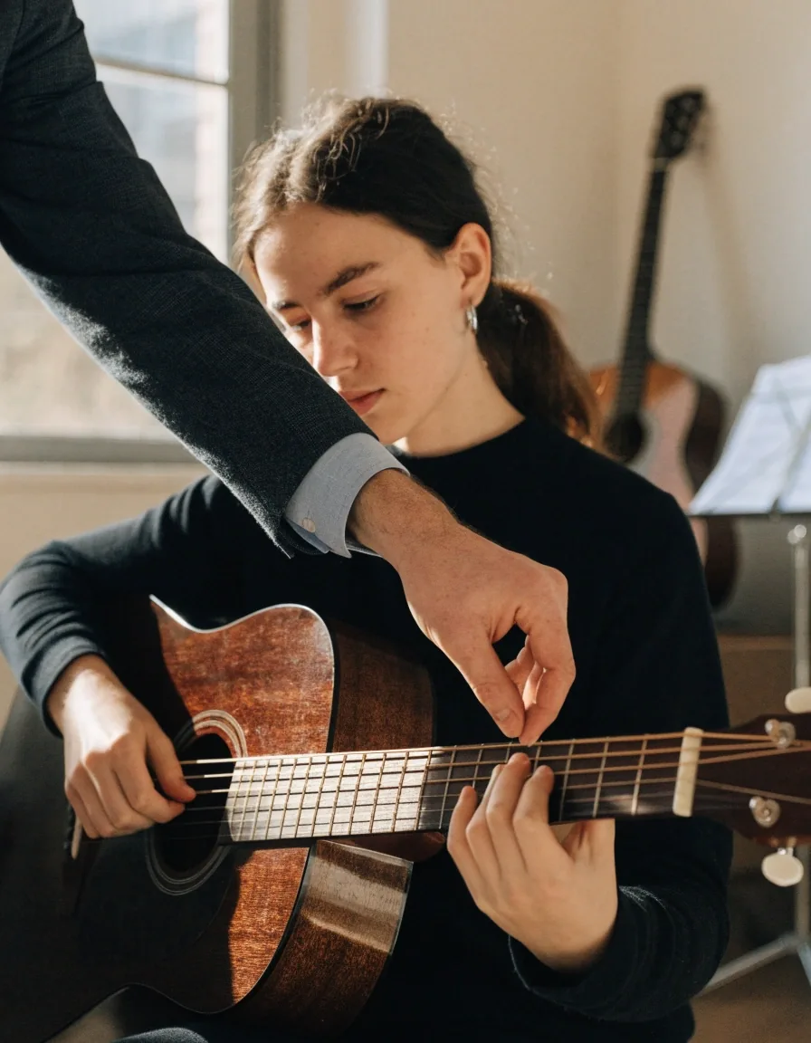 A quiet teaching room at the end of the day with a guitar on a stand and warm light across the floor
