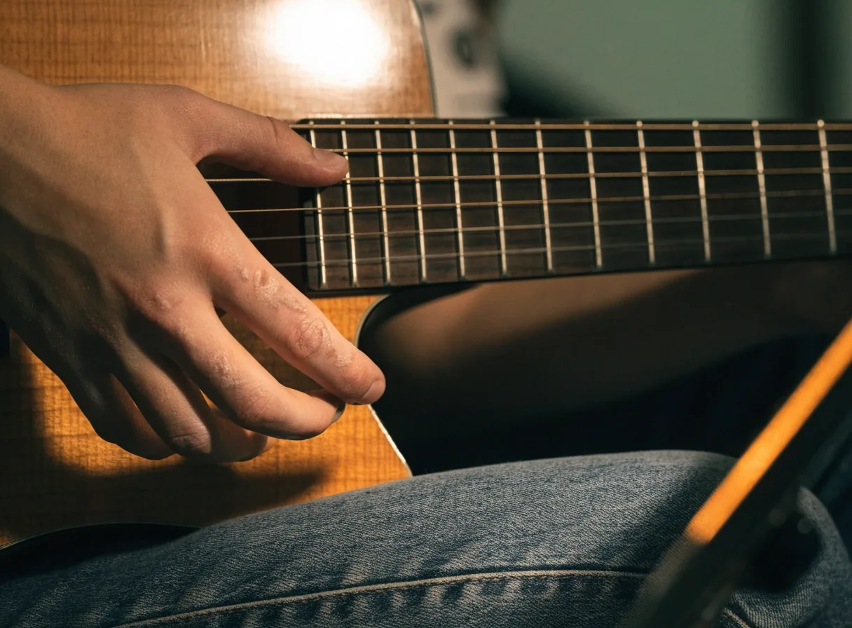 Beginner's hand pressing an open chord on an acoustic guitar